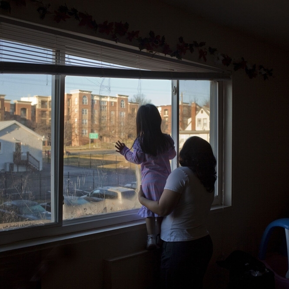 Family looking out of a window in a city