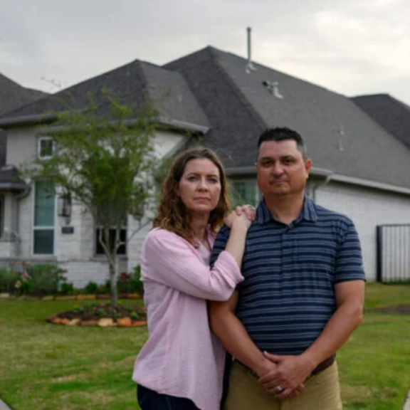 Couple stands in front of their home.