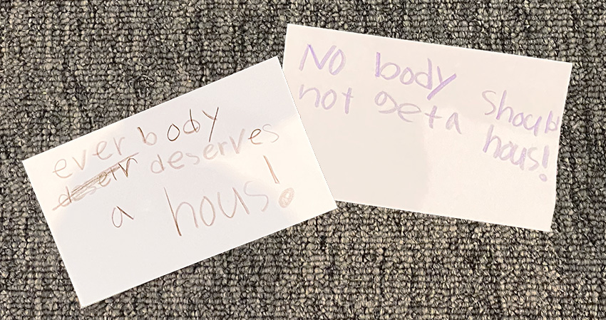 Notes with affordable housing messages in a child's handwriting.