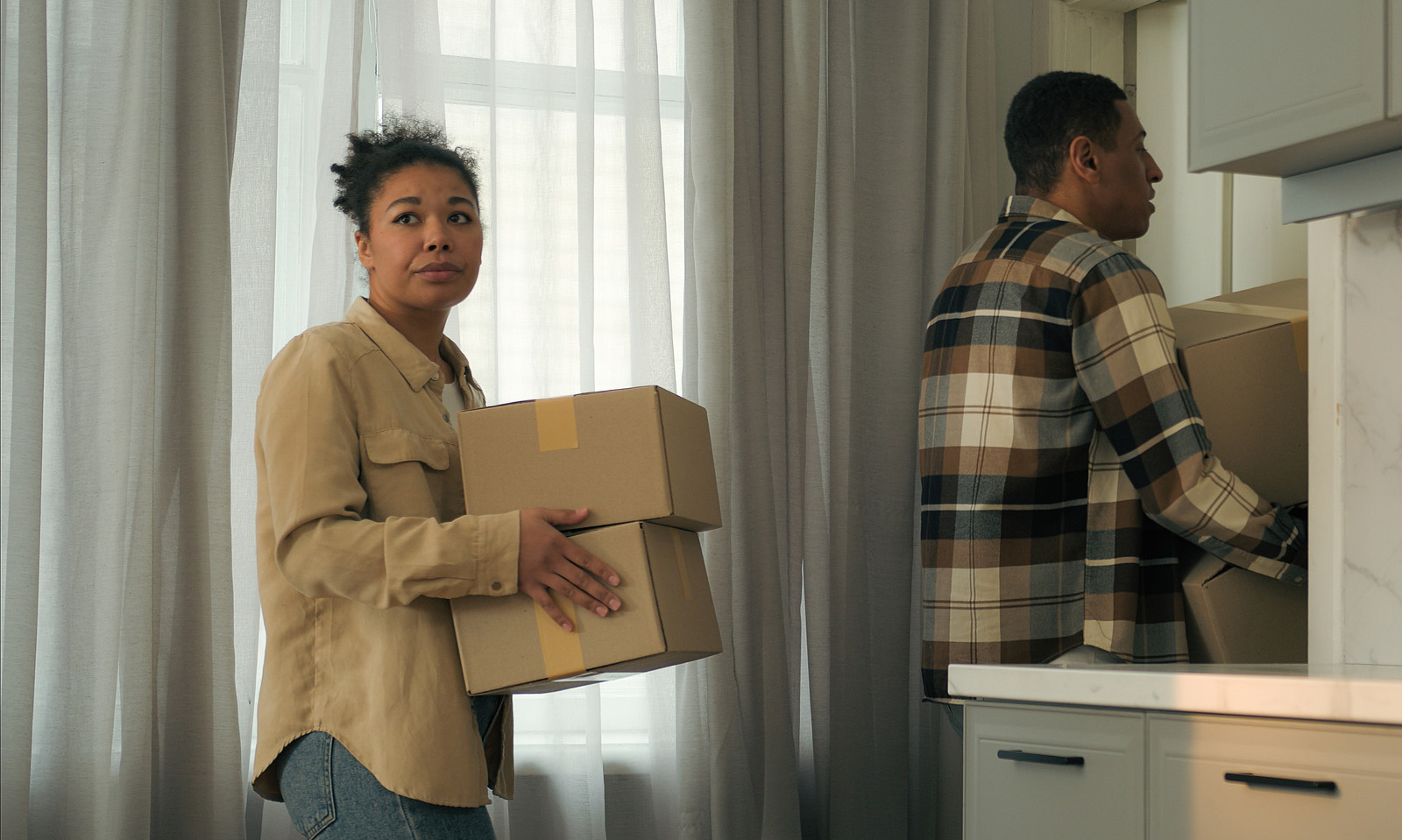 Two people moving boxes out of a home.