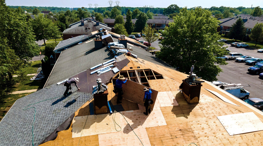 Workers install new roofing on a multifamily building.