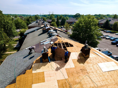 Workers install new roofing on a multifamily building.