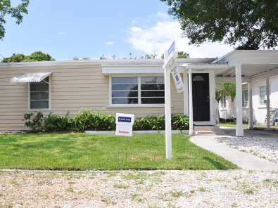 Small home with for sale sign in front.
