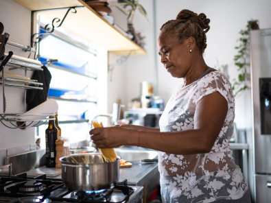 Older adult woman cooking dinner at home.