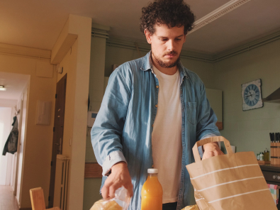 Man unpacking groceries in apartment kitchen.