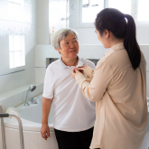 Aide caring for older woman in her home.