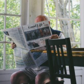 Older adult man reading the paper at home.
