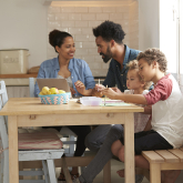 Parents with young children at kitchen table.
