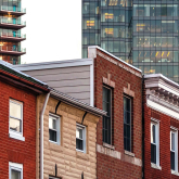 Older rowhouses with modern apartment tower in the background.