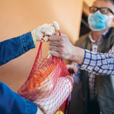 Person delivering groceries to older adult at home.