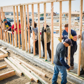 People framing wall in house under construction.