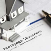 Model of a house on top of mortgage paperwork.