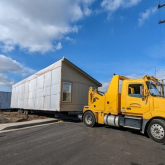 Truck pulling manufactured house.