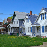Row of small wooden houses with front yards.