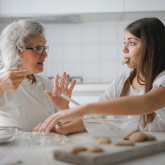 Older woman and teenage granddaughter make cookies.