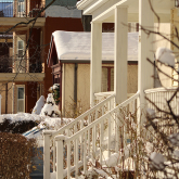Snowy front porch and houses in the background.