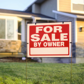 For-sale sign in yard of small home.