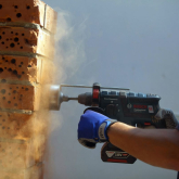 Man drilling into brick wall.