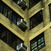 Air conditioners in apartment building windows.