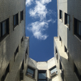 View of the sky looking up through the courtyard of an apartment building.
