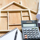 Collection of home remodeling equipment including calculator, measuring tape, and plans.