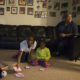 A disabled woman is photographed in her Washington, D.C., apartment, which she can barely afford with public assistance, with family members.