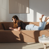 Young woman working on couch in apartment.