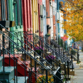Row of townhouses with front staircases along street.