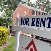 For rent sign in front of brick houses.