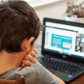 Young boy staring at laptop screen at home.