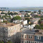 Triple decker apartment buildings in a dense neighborhood.