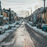 Snowy residential street with small homes.