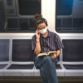 Man sitting and reading on a subway train.