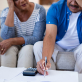 Older couple paying bills looking worried.