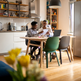 Two people reviewing bills at kitchen table.