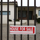 Home with gate and "house for sale" poster.