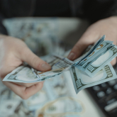 Person counting cash with calculator nearby.