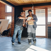 Two people examine plans for a remodeling project