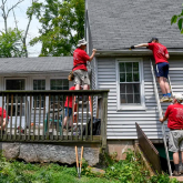 People on ladders working on the outside of a house.