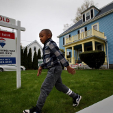 Home with four-sale sign and child in the front yard.