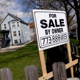 Sign saying "for sale by owner" in front of single-family house.