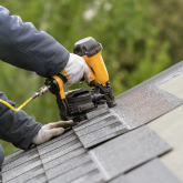 Person installing new roof on house.