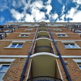 View looking up the face of an apartment building, towards the sky.