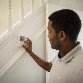 Person adjusting thermostat in home.