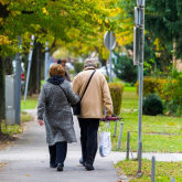 Older couple walking down sidewalk.