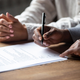 Two people signing homeownership documents.