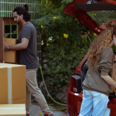 Young couple loading possessions into car.