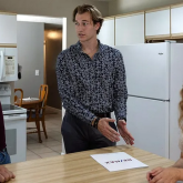 People gathered around a kitchen table talking.