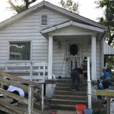 View of a small house with wheelchair ramp being installed.