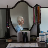 View of older woman sitting by mirror.